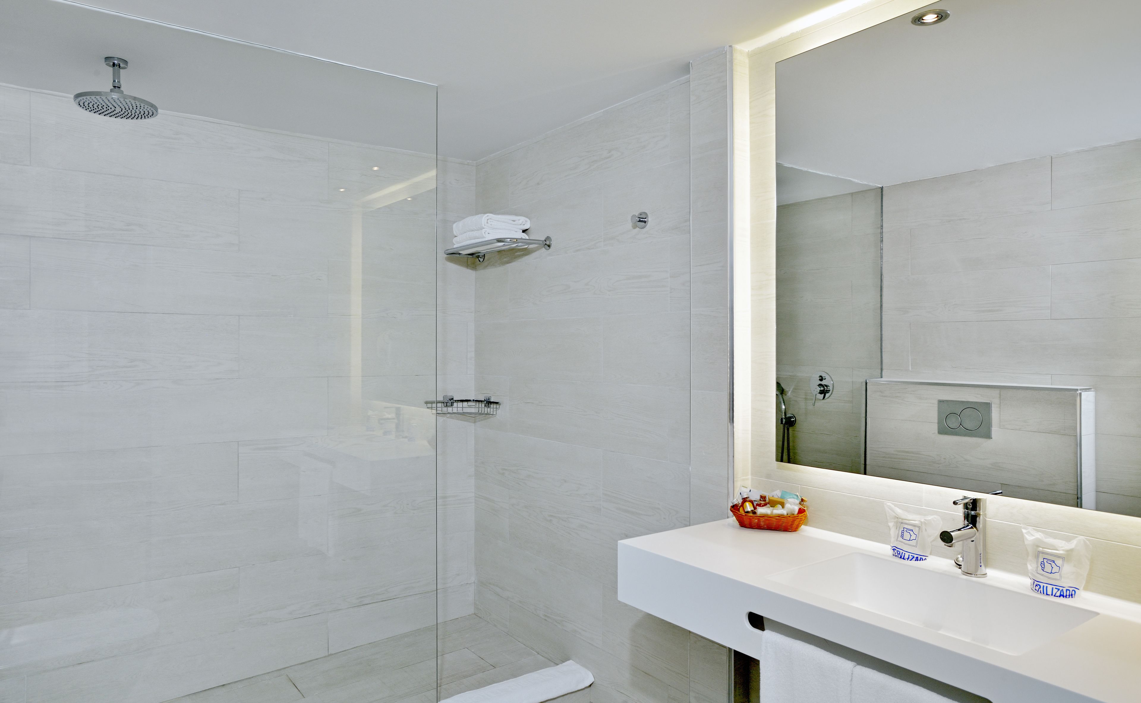 Une salle de bain moderne avec une douche à parois de verre, un lavabo blanc avec un miroir et un porte-serviettes.