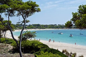 Una playa con agua turquesa cristalina, barcos y gente.