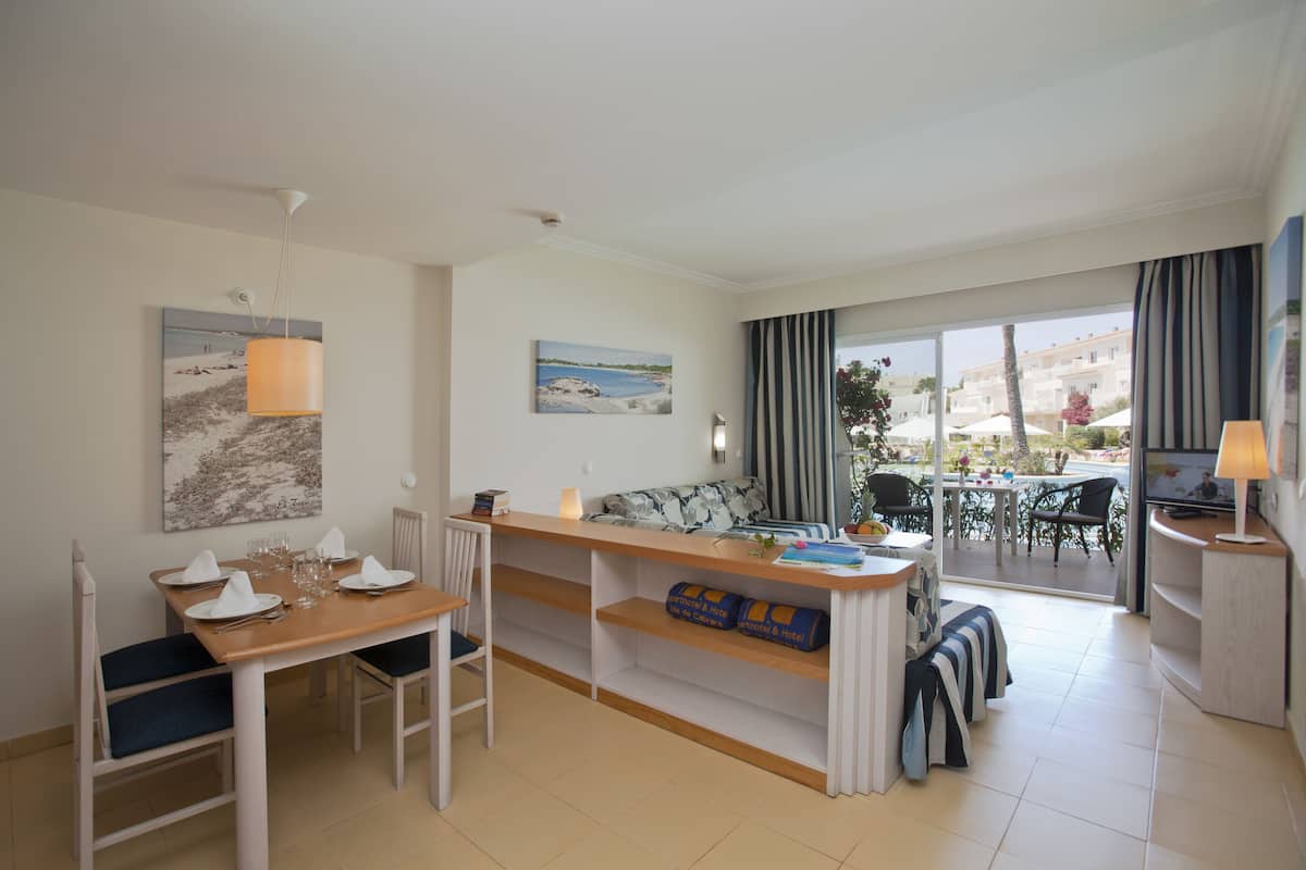 Ein modernes Hotelzimmer mit Essbereich, einer Couch und einem Balkon mit Meerblick.