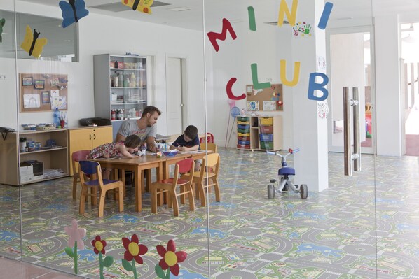 Una sala de juegos para niños, con piso colorido, una mesa de madera y sillas.