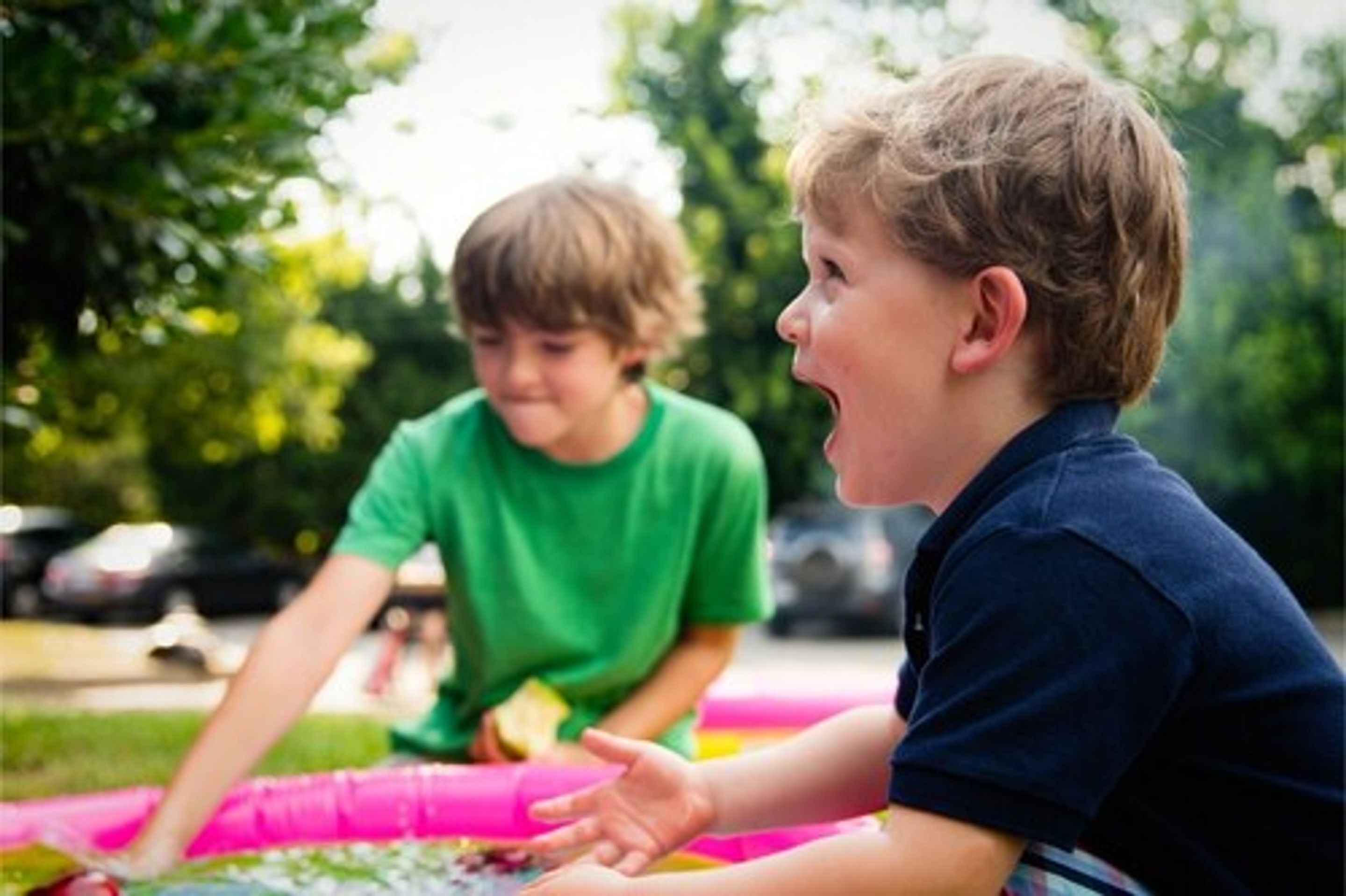Twee kinderen spelen met speelgoed op een tafel buiten.