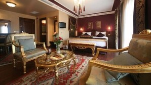 A hotel room with a large bed, two ornate armchairs, a small table with a vase, and a patterned carpet. - Garden House Hotel - Special Class (Istanbul)