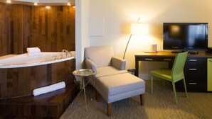 A hotel room with a bathtub, a desk with a TV, a chair, and a lamp. - Hôtel Champlain Vieux Québec (Québec City)