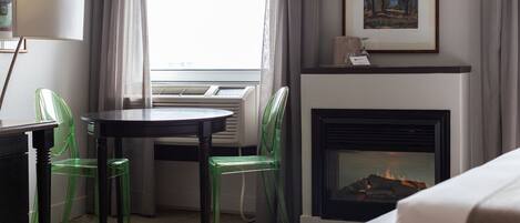 Una habitación de hotel con chimenea, una mesa de comedor y dos sillas.