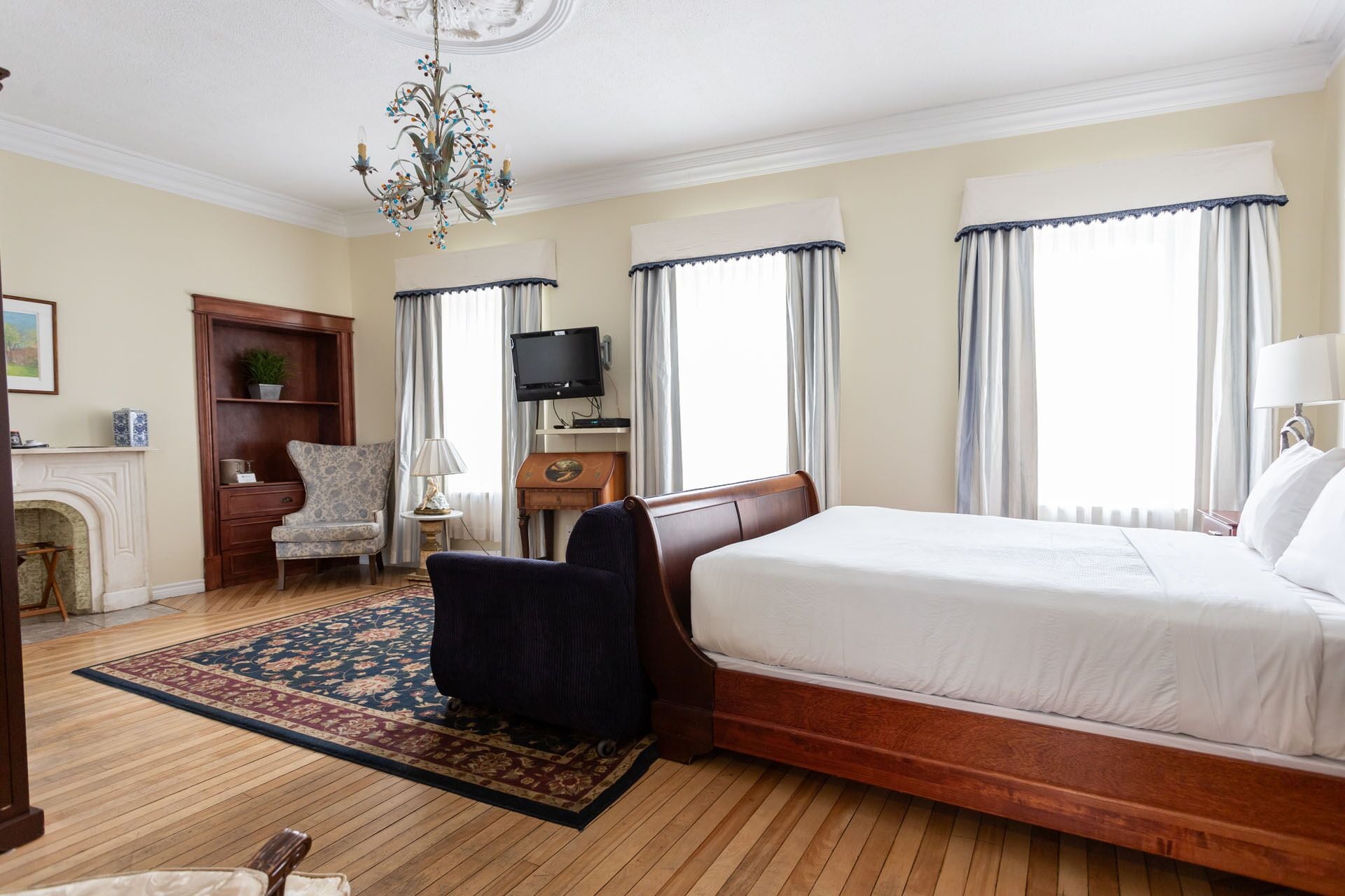 A hotel room with a large bed, a television, a fireplace, and a chandelier.