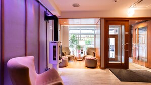 A lobby with a reception desk, two armchairs, a small table, and a potted plant. - Hôtel Champlain Vieux Québec (Québec City)