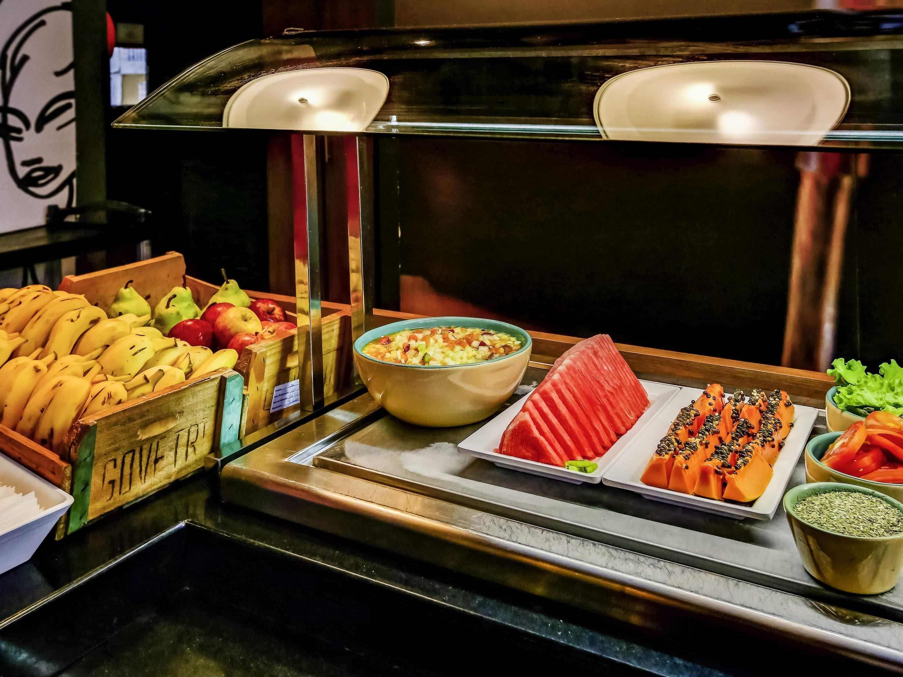 A buffet with various fruits and vegetables, including bananas, apples, and watermelon.