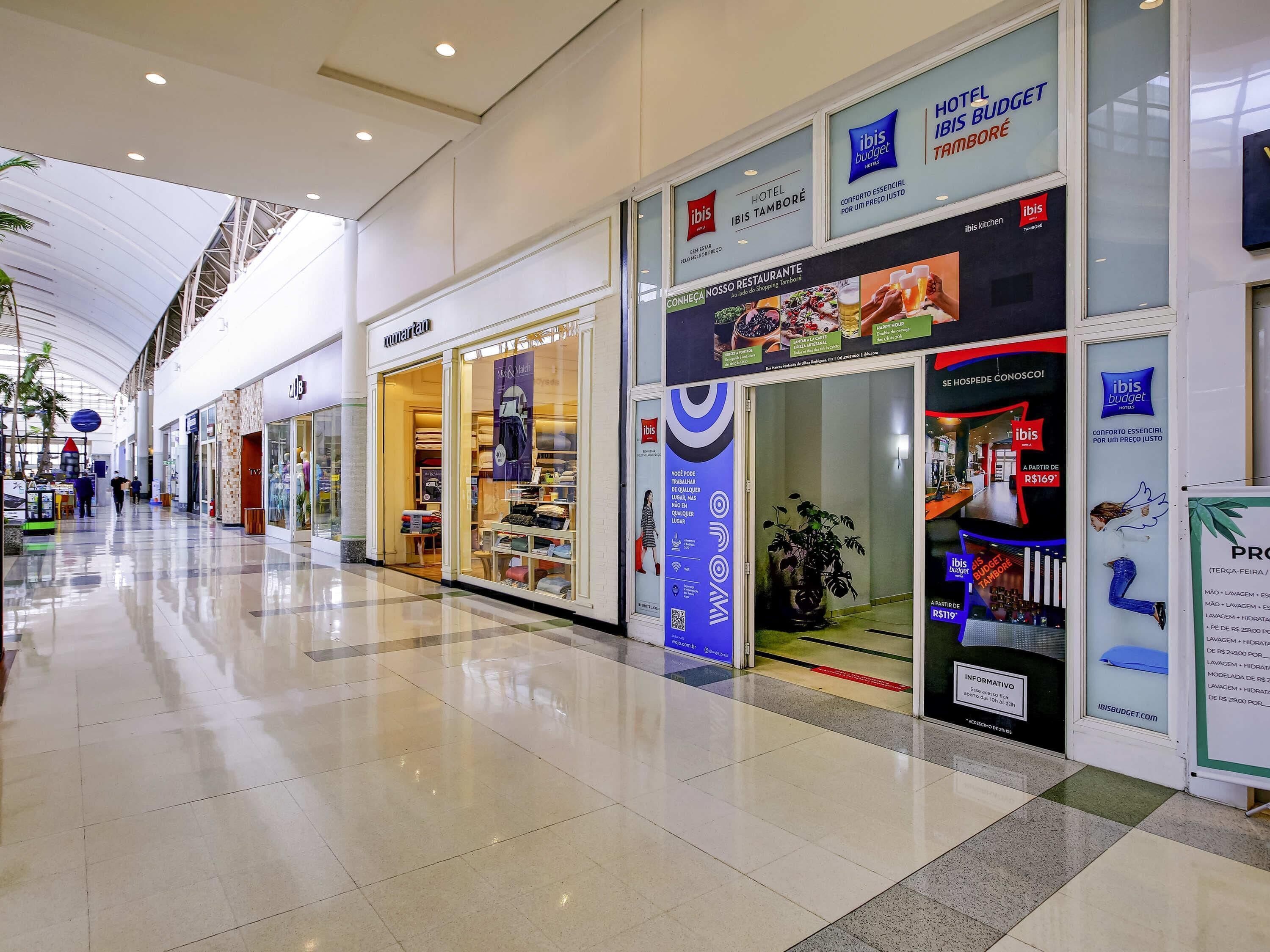 A hotel interior with a modern design, a visible restaurant, and a sign for ibis budget hotel.