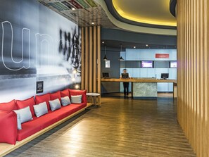 A modern lobby with a red sofa, wooden paneling, and a reception desk with an 'ONLINE CHECK-IN' sign. - ibis Tamboré (Barueri)