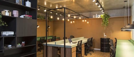 Un espacio de oficina moderno con una larga mesa de conferencias, varias sillas y una estantería con diversos objetos.