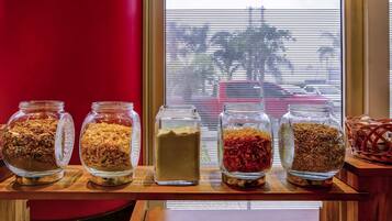 A wooden shelf with five glass jars containing various food items.