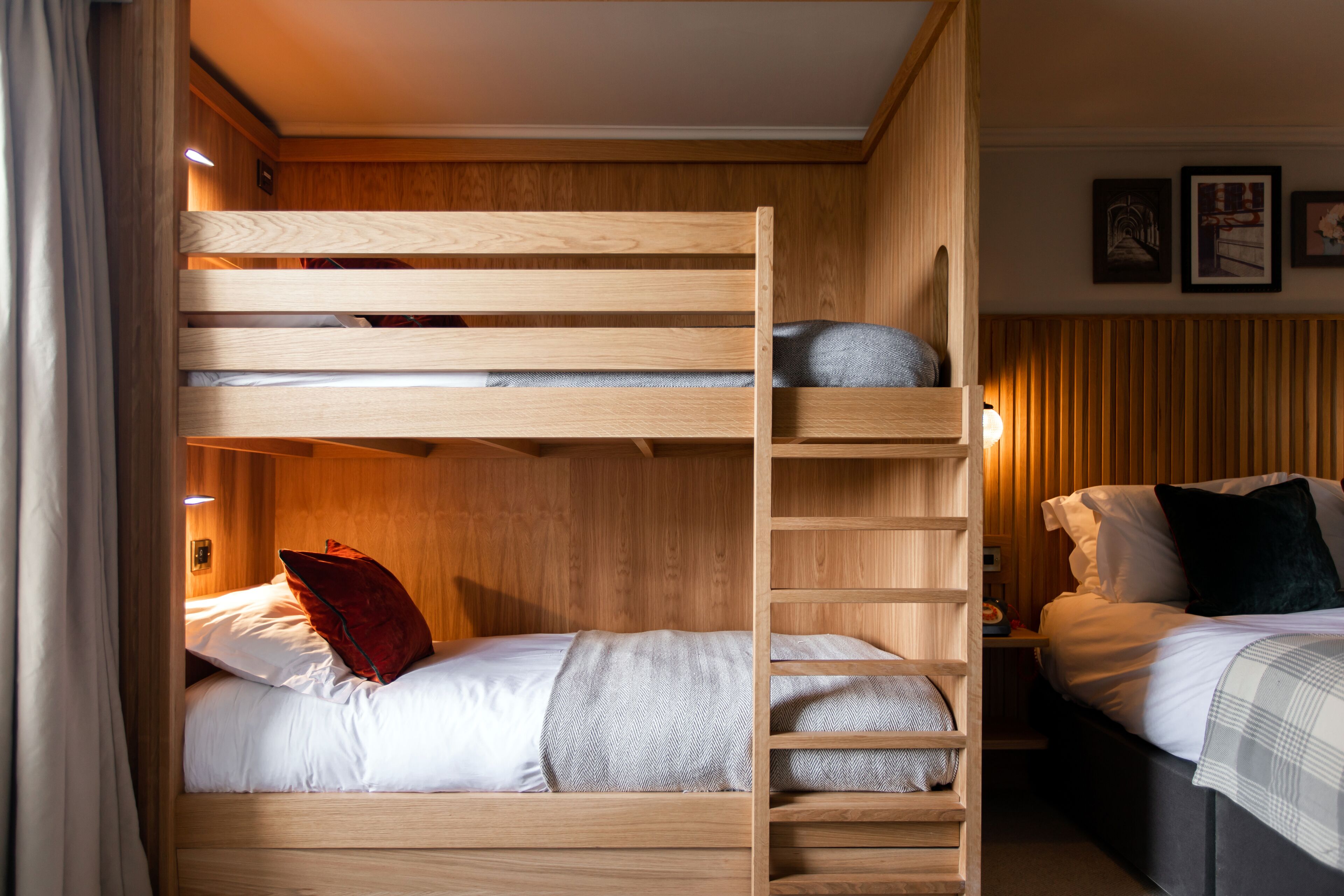 A bunk bed room with wooden walls and a nightstand with a lamp.