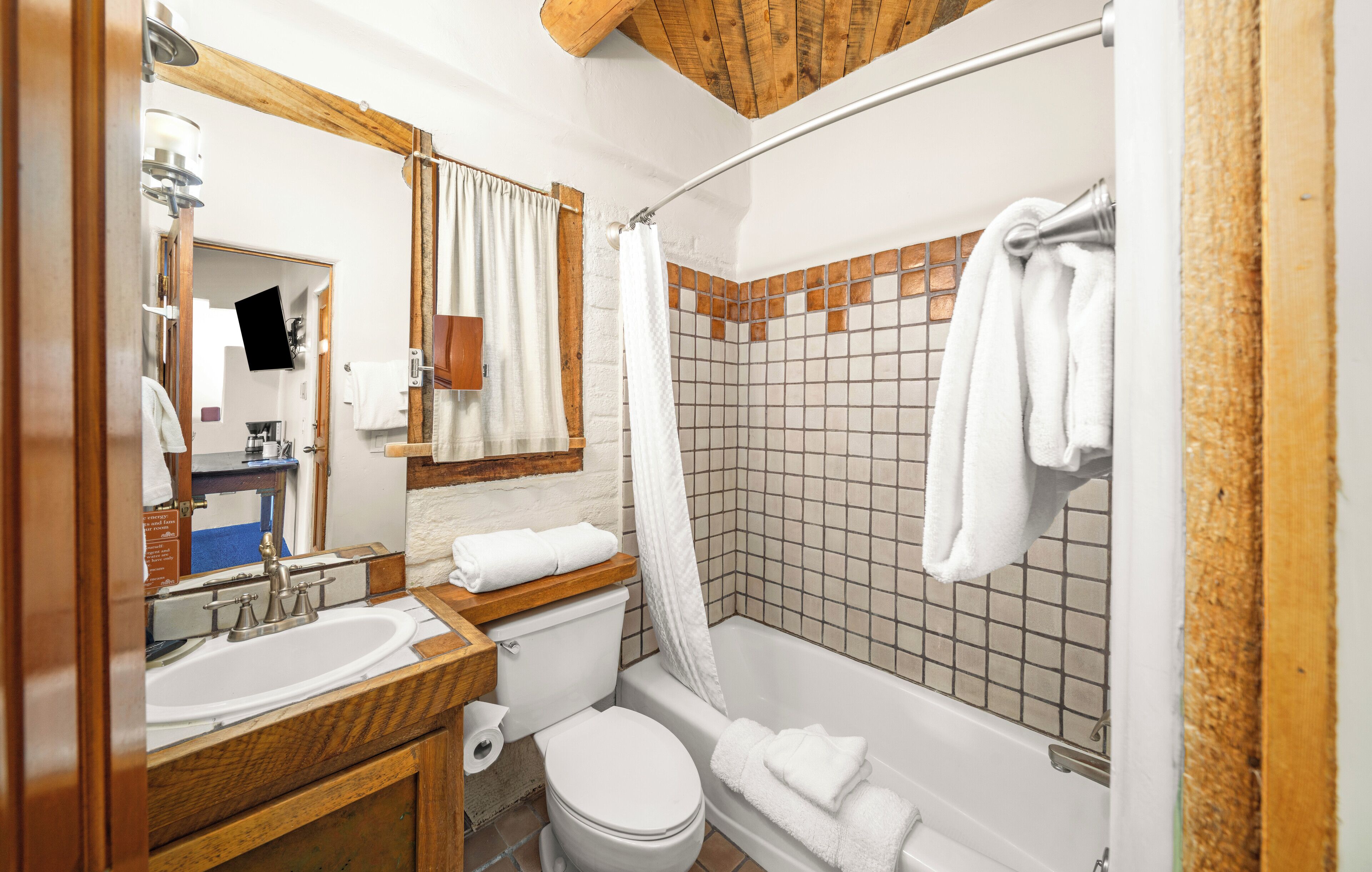 A bathroom with a wooden vanity, a sink, a toilet, and a shower area with tiled walls.