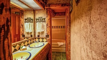 Un bagno con pareti in legno, un ampio specchio, due lavabi con piastrelle decorative e una vasca.