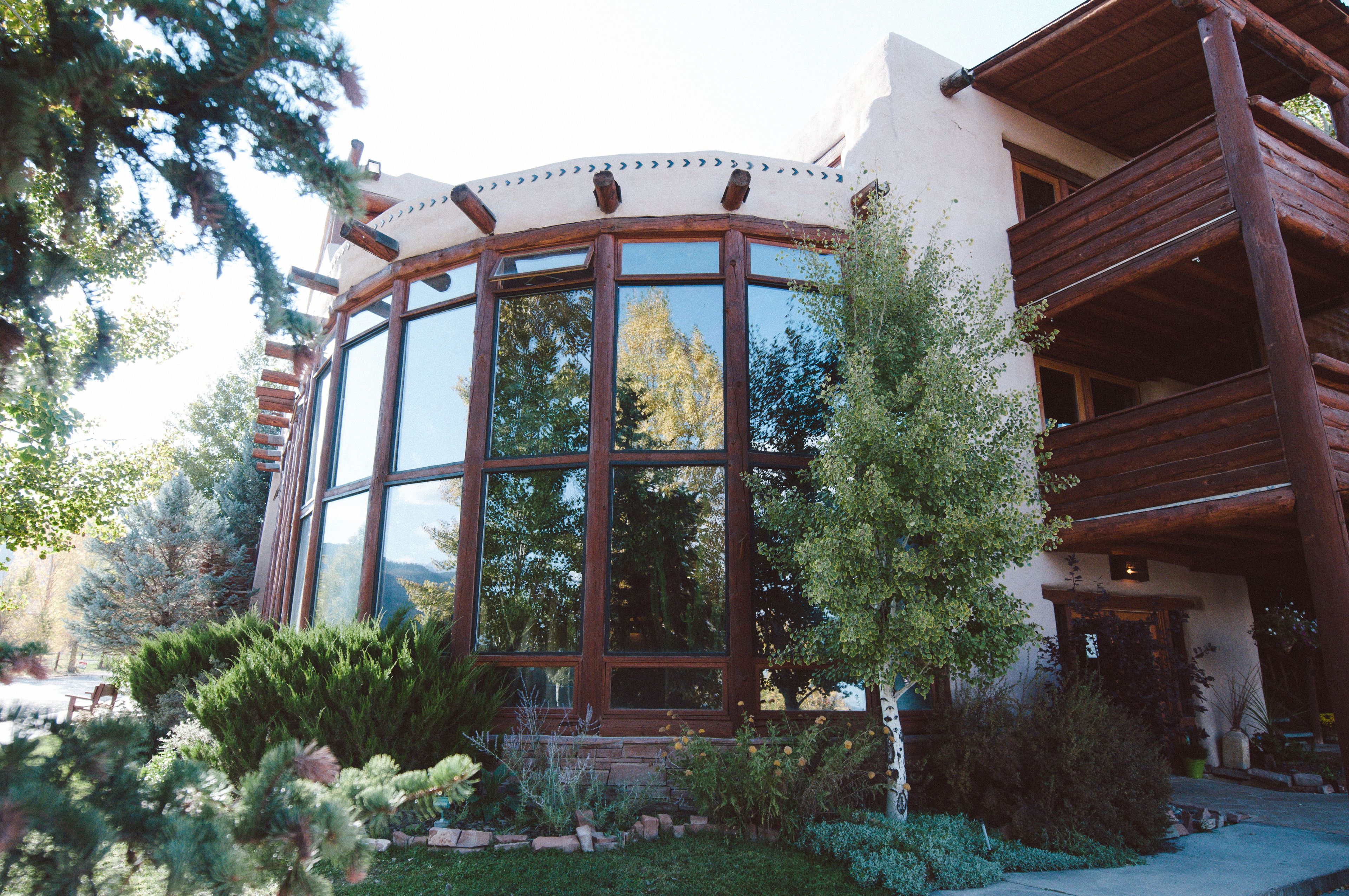 A building with a large circular window, wooden balconies, and a garden with various plants.