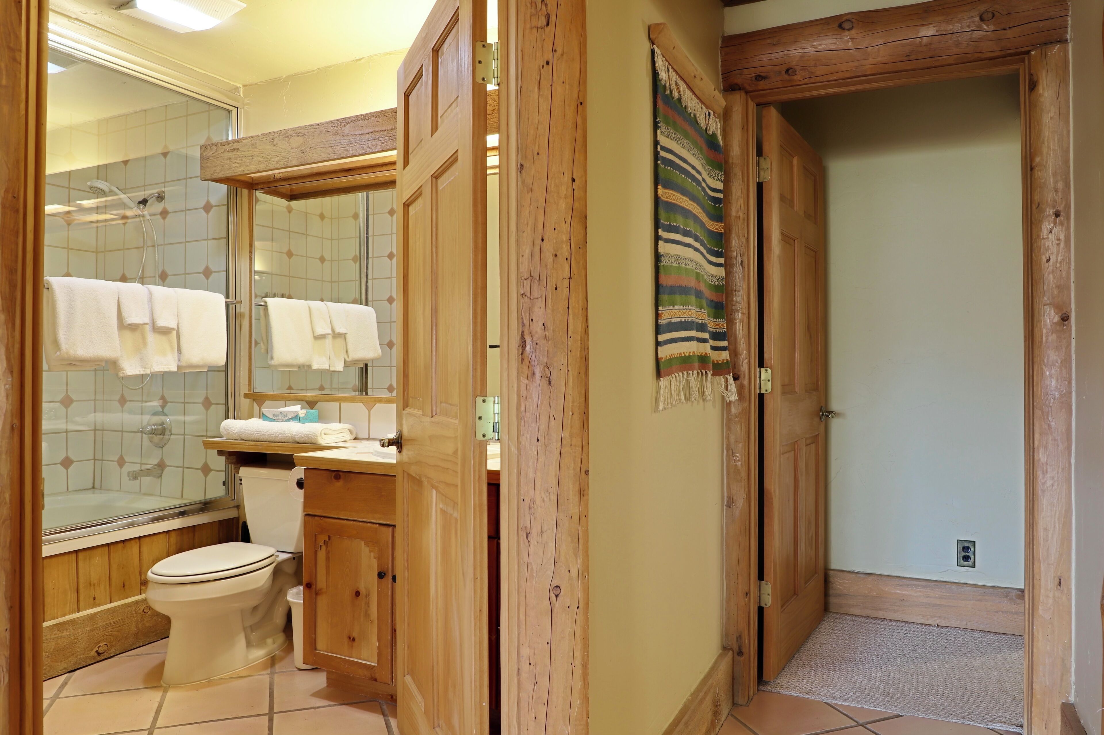 A bathroom with a glass-enclosed shower, a wooden vanity, and a large mirror.