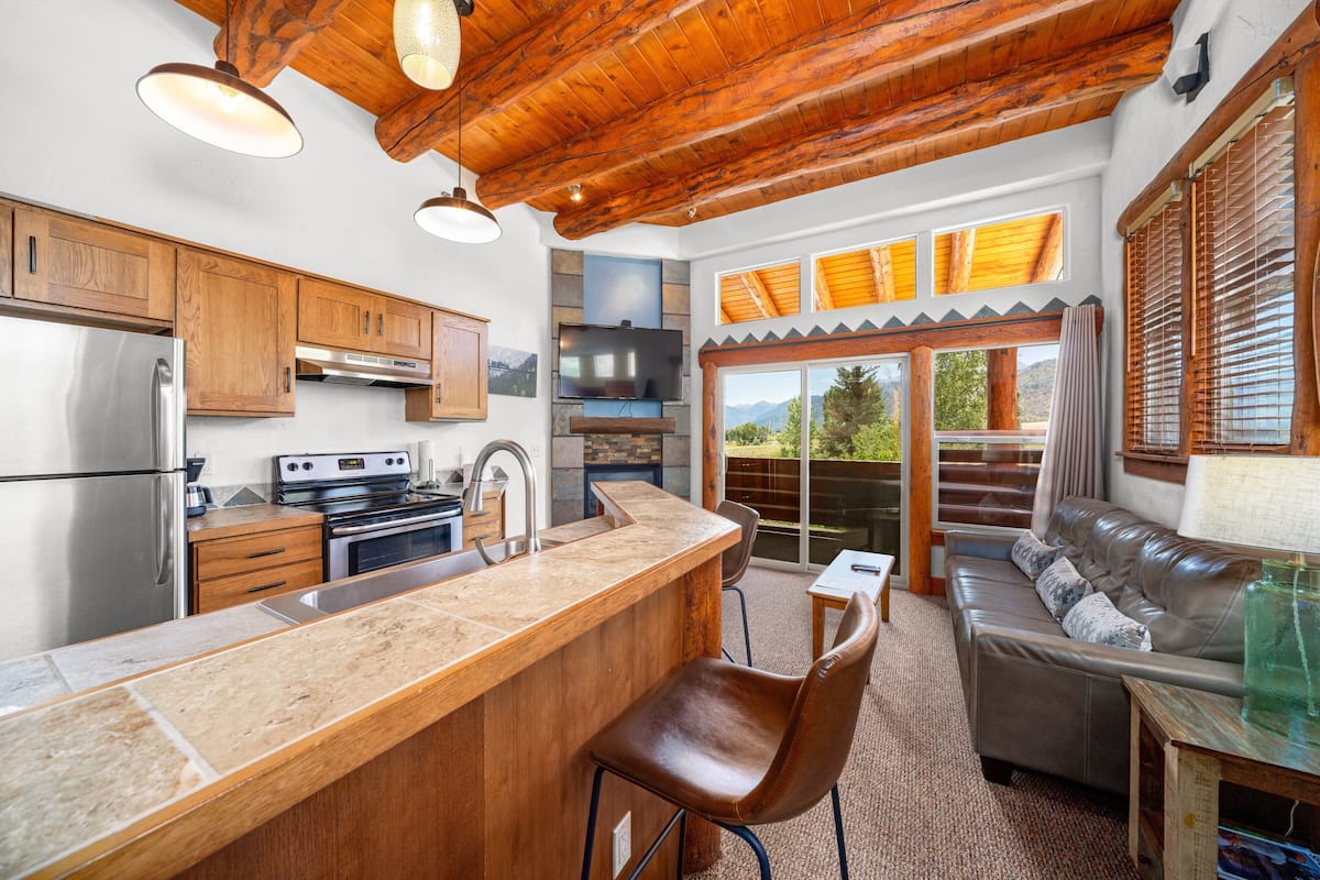 A spacious kitchen with wooden cabinets, a stainless steel refrigerator, and a large island with a sink.