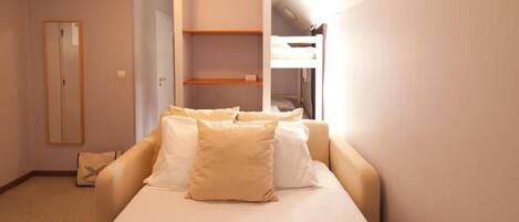 A hotel room with a bed, a wardrobe, and a built-in shelf unit.
