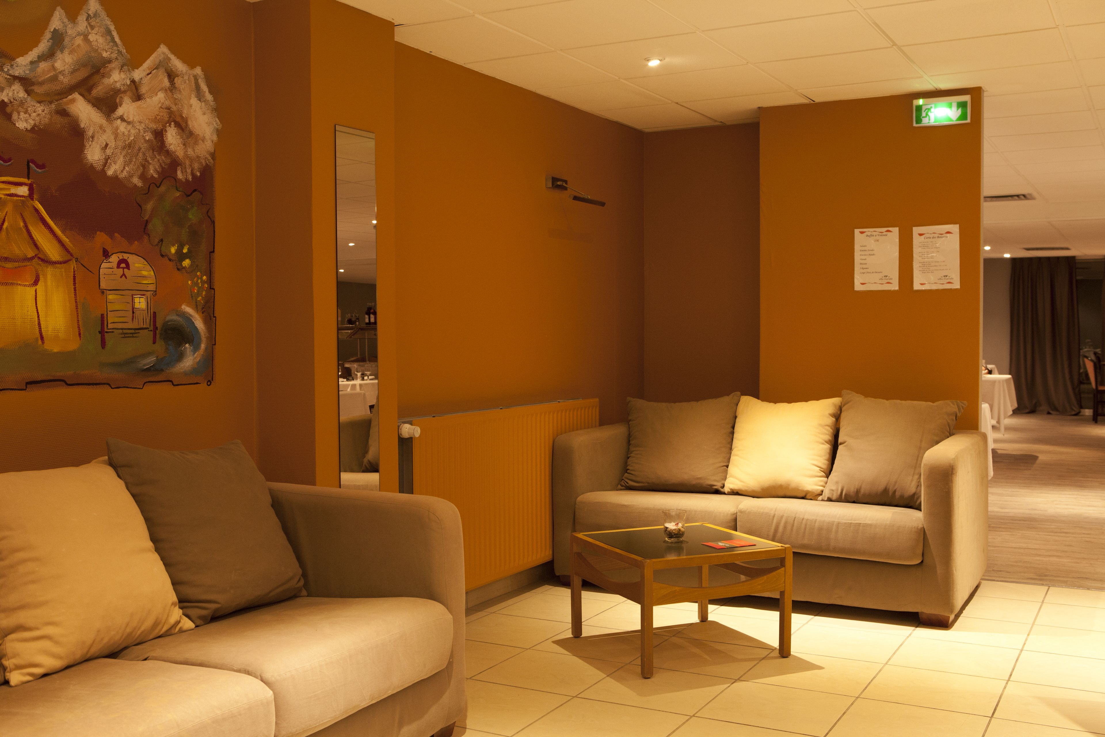 Un vestíbulo de hotel con dos sofás, una mesa de centro y un mural en la pared.