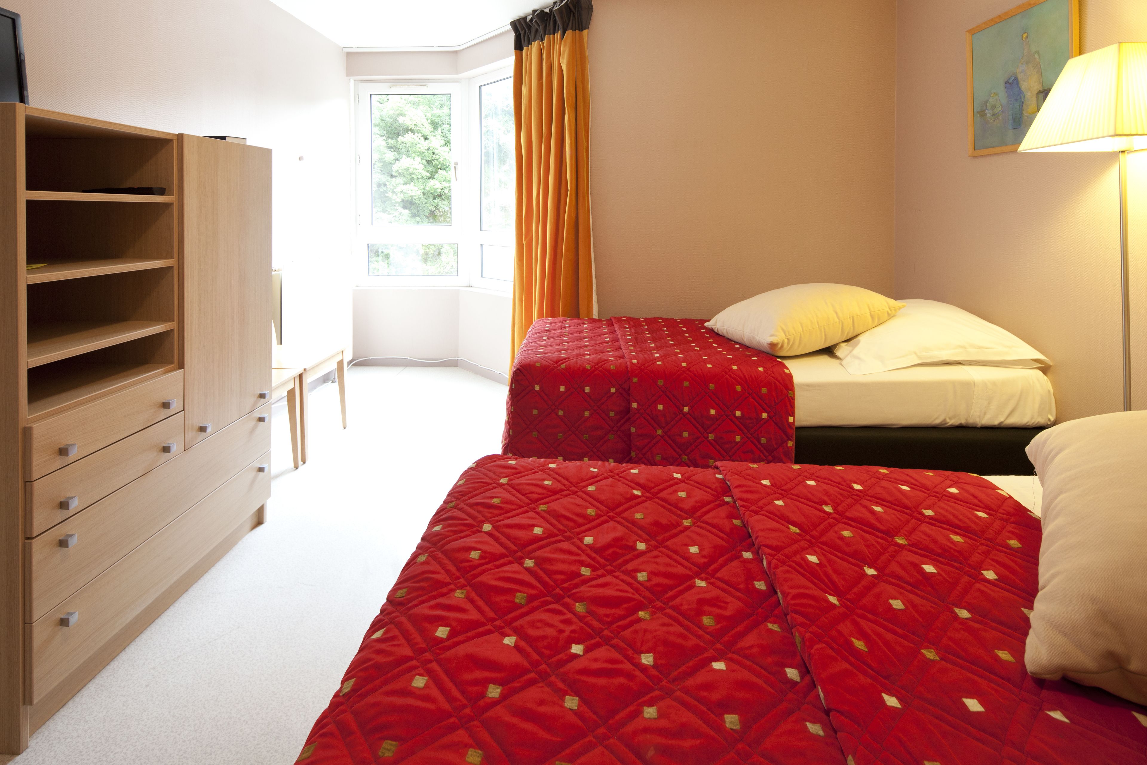 Ein Schlafzimmer mit zwei Betten, einem Holzkapuzenpaneel und einem Fenster mit Vorhängen.