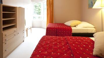 Ein Schlafzimmer mit zwei Betten, einem Holzkapuzenpaneel und einem Fenster mit Vorhängen.
