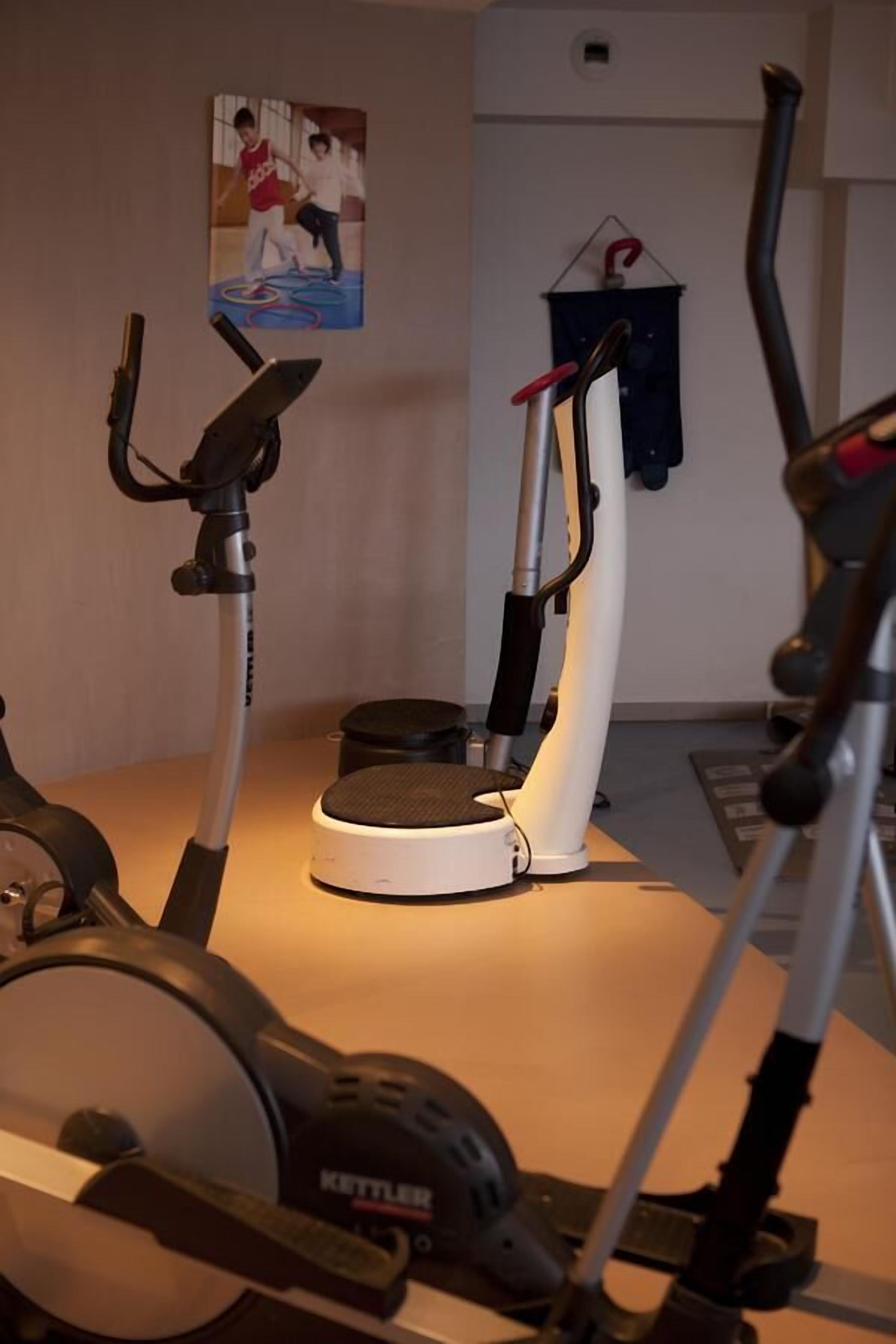 A home gym with an elliptical machine, a stationary bike, and a treadmill.