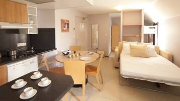 A compact hotel room with a kitchenette, a dining area, a bed, and a walk-in closet.