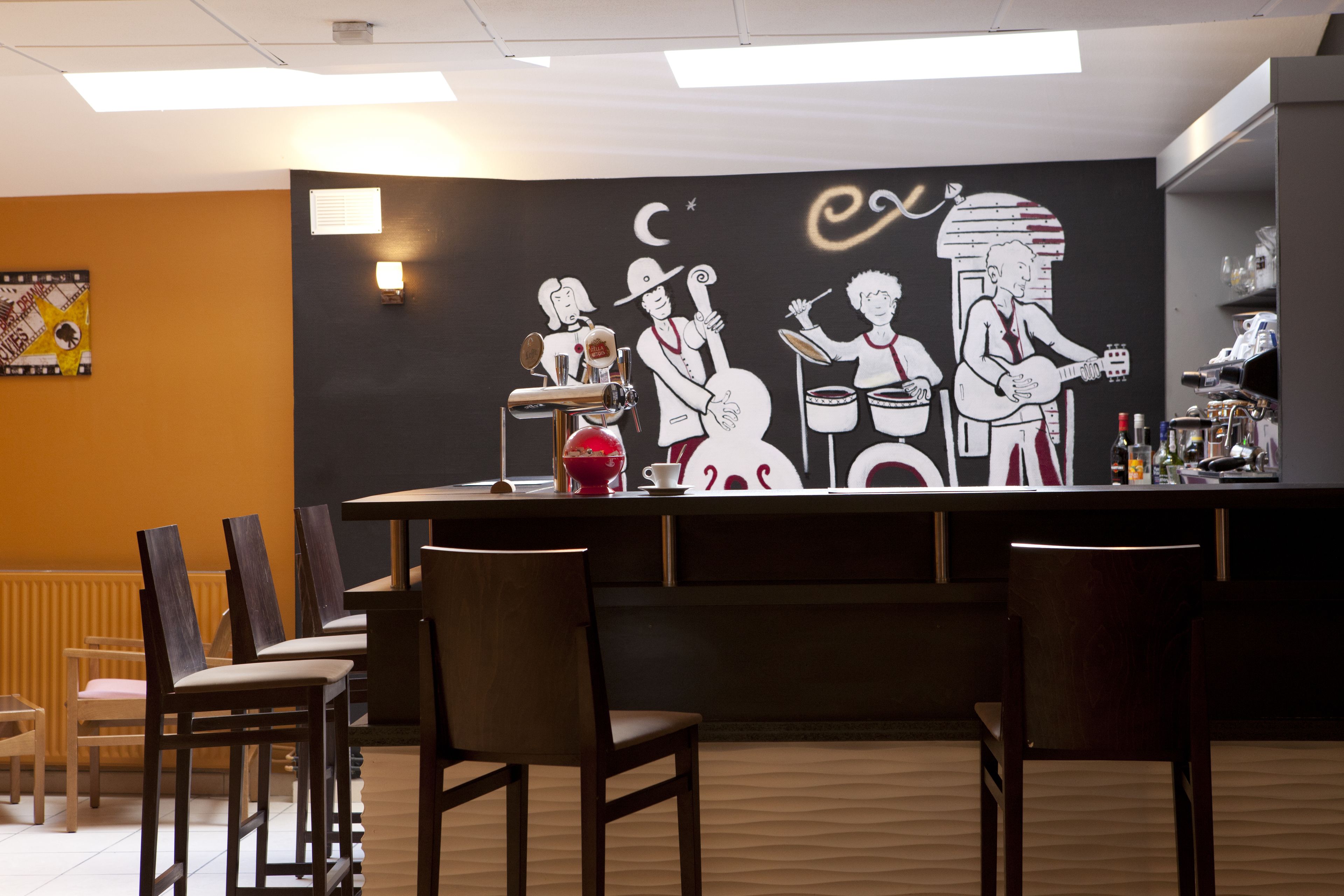 A bar area with a mural of musicians, bar stools, and a counter with bottles.