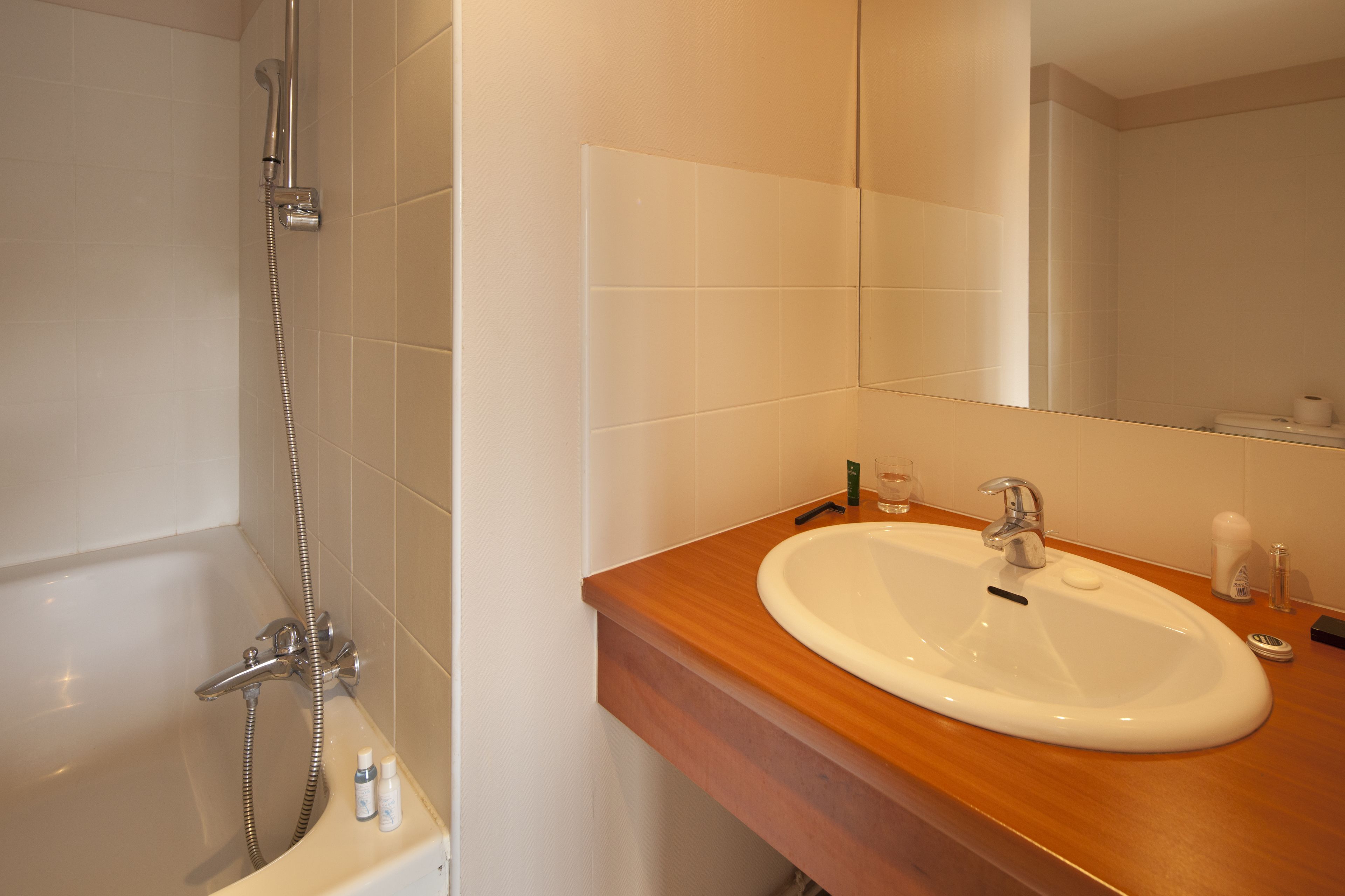 A bathroom with a bathtub, a sink, and a mirror.