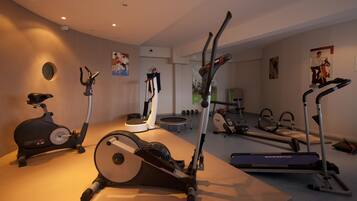Un gimnasio en casa con bicicletas estáticas, una cinta de correr y una máquina de remo.