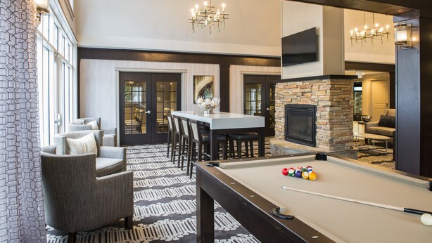 A pool table with billiard balls, a fireplace, and a dining area with chairs and a table. - Residence Inn by Marriott Worcester (Worcester)
