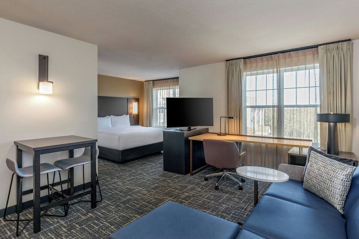 A hotel room with a bed, a desk with a chair, a sofa, and a TV.