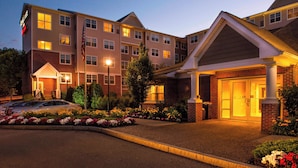 A multi-story hotel with a brick facade, a well-lit entrance, and a parking area with cars. - Residence Inn by Marriott Worcester (Worcester)