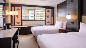 Une chambre d’hôtel avec deux lits, un bureau, une chaise, une lampe et une vue sur les immeubles par la fenêtre.