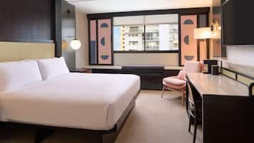 Una habitació d'hotel amb un llit gran, escriptori, cadira i vista a la ciutat per la finestra.