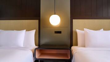 A hotel room with two beds, a central nightstand, and a wall-mounted light fixture.