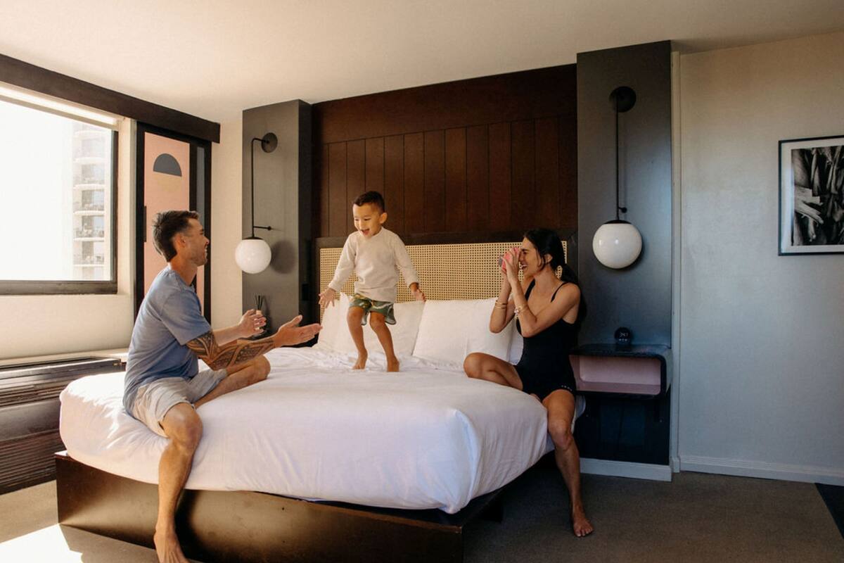 Une chambre d’hôtel moderne avec un grand lit, une table de chevet et une lampe fixée au mur.