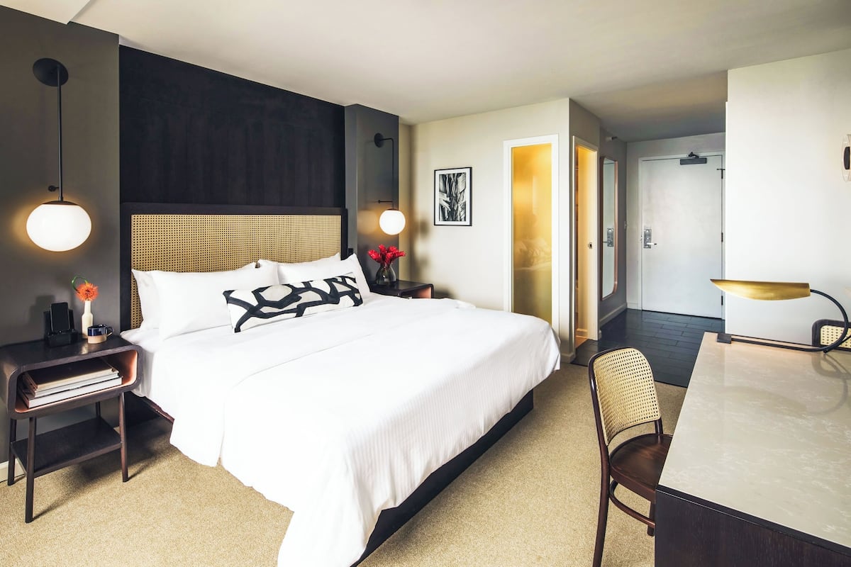 Una habitación de hotel con una cama grande, mesitas de noche, un escritorio y una silla.