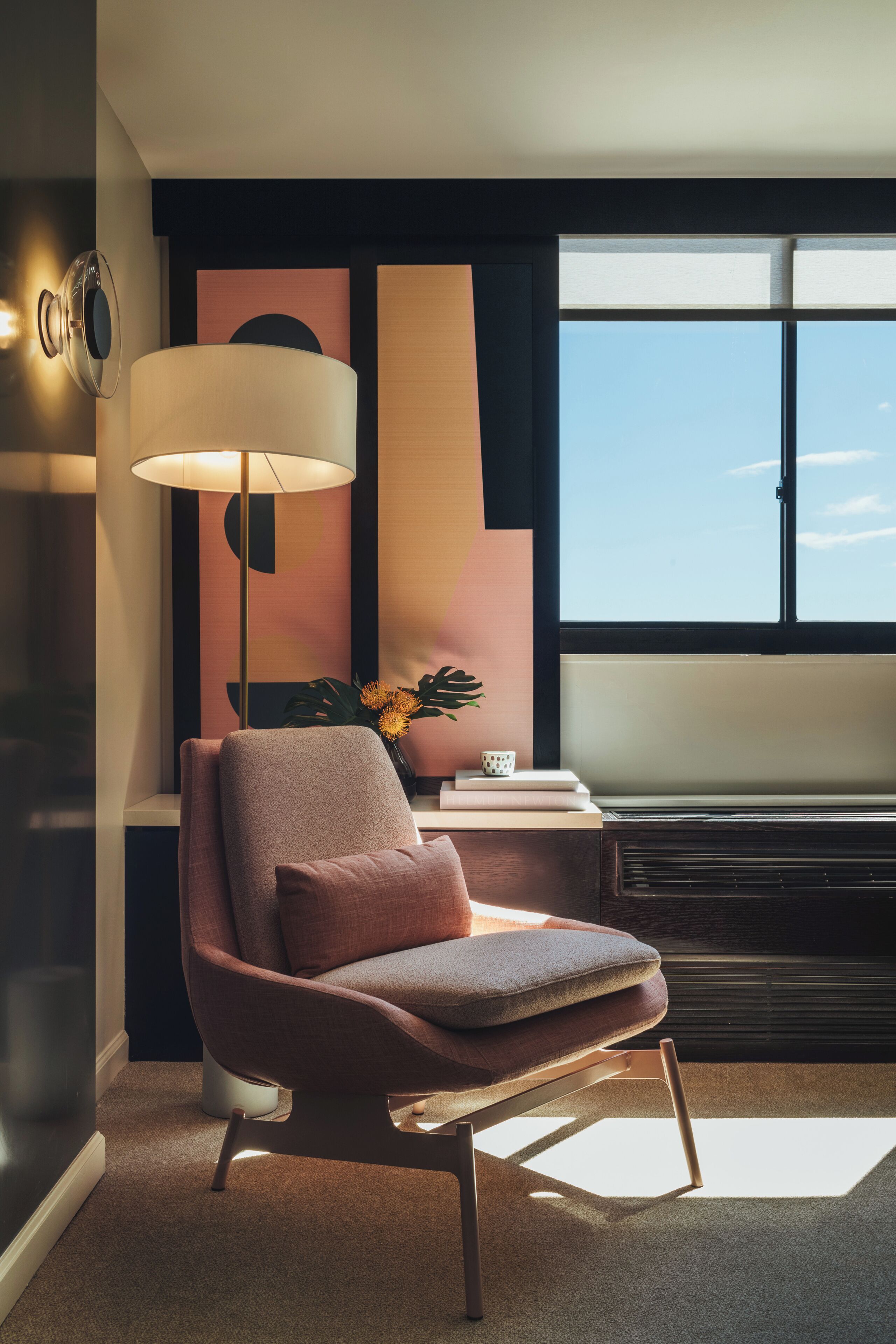 Ein modernes Zimmer mit großem Fenster, einem zeitgemäßen Sessel, einer Stehlampe und einem Wanddekor.