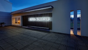 Une façade d’hôtel moderne, avec une enseigne lumineuse bien visible portant l’inscription « HÔTEL KLAUSTUR ».