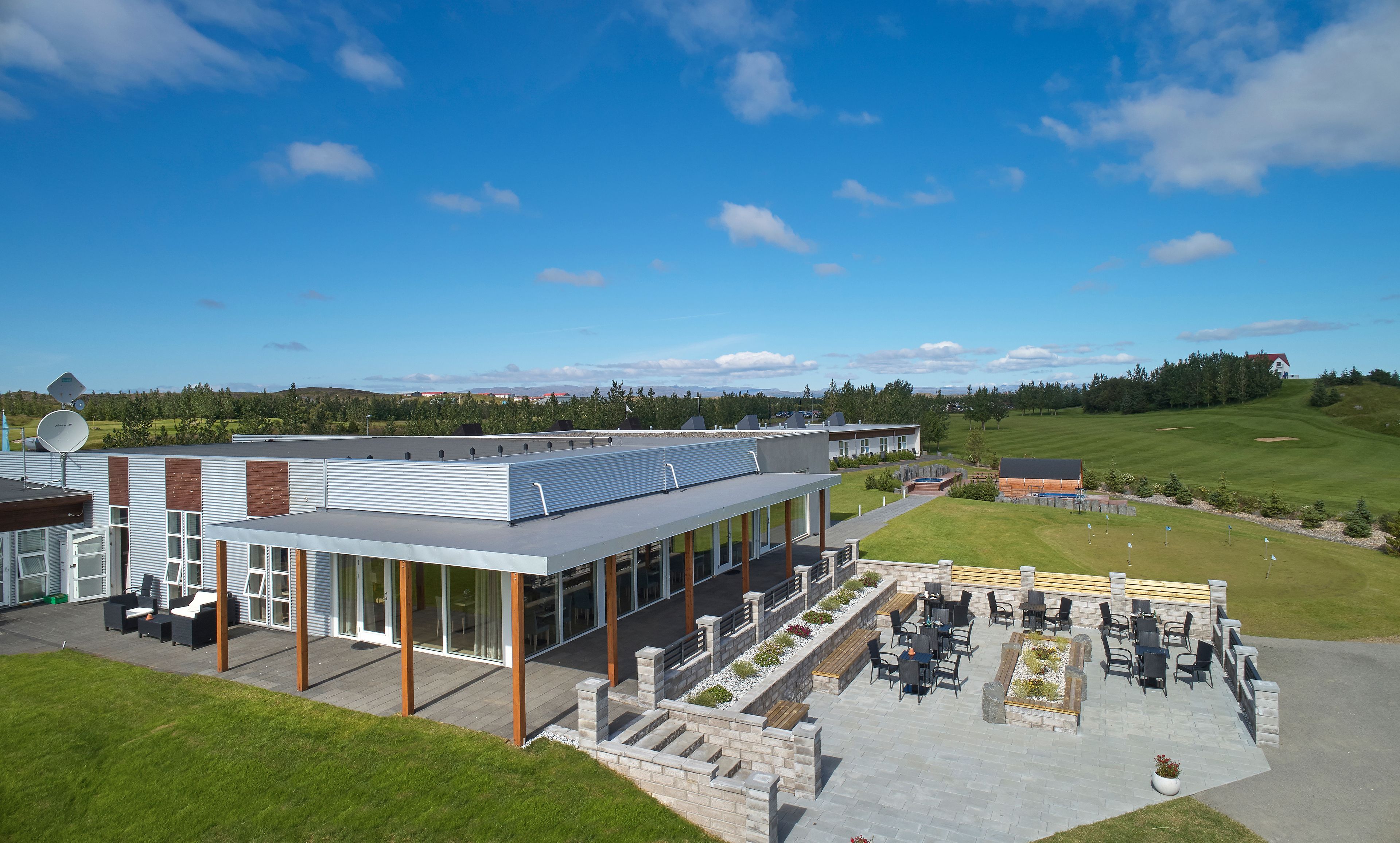 A modern building with a flat roof, large windows, and a patio area with outdoor seating.