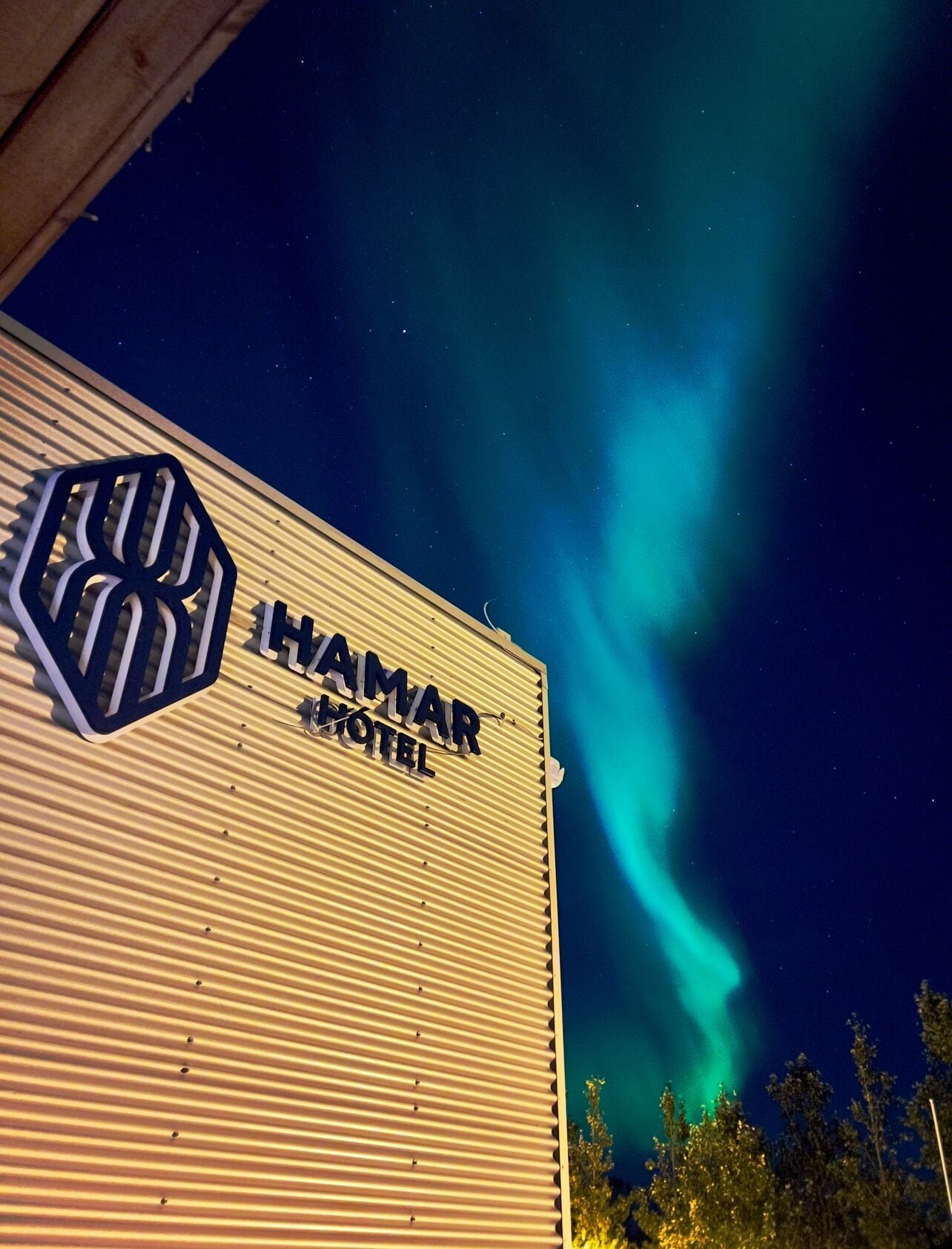 The exterior of the Hamar Hotel with a view of the Northern Lights.