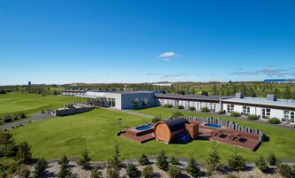 A modern hotel with a swimming pool, outdoor seating, and a large lawn.