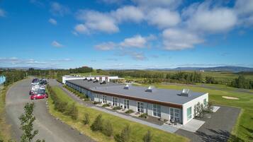 A modern building with a parking lot and a view of a golf course and mountains.