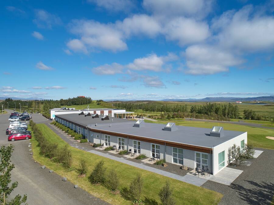 A modern building with a parking lot and a view of a golf course and mountains.