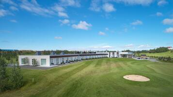 Un hotel moderno con una larga fila de habitaciones, un césped bien cuidado y un campo de golf.