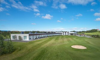 Un hotel moderno con una larga fila de habitaciones, un césped bien cuidado y un campo de golf.