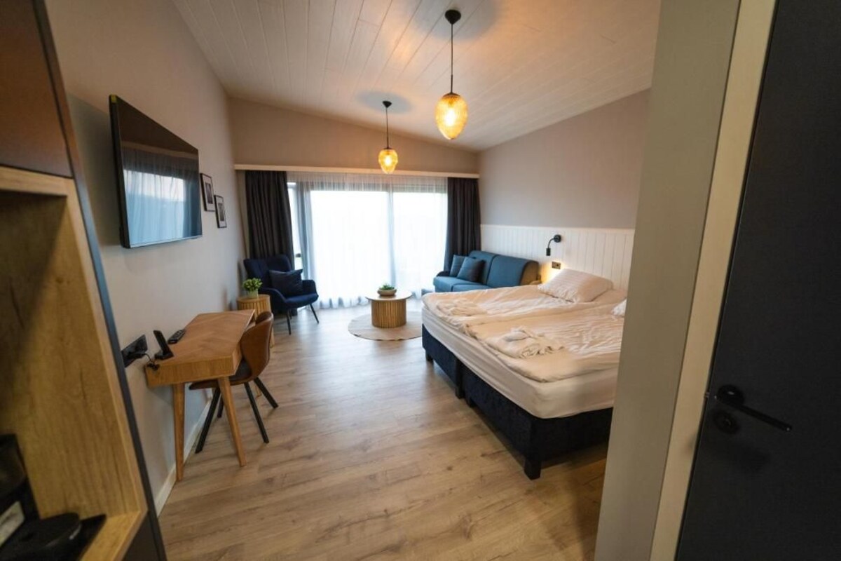 Habitación de hotel con cama, escritorio, silla, mesa redonda, sofá y televisor en la pared.