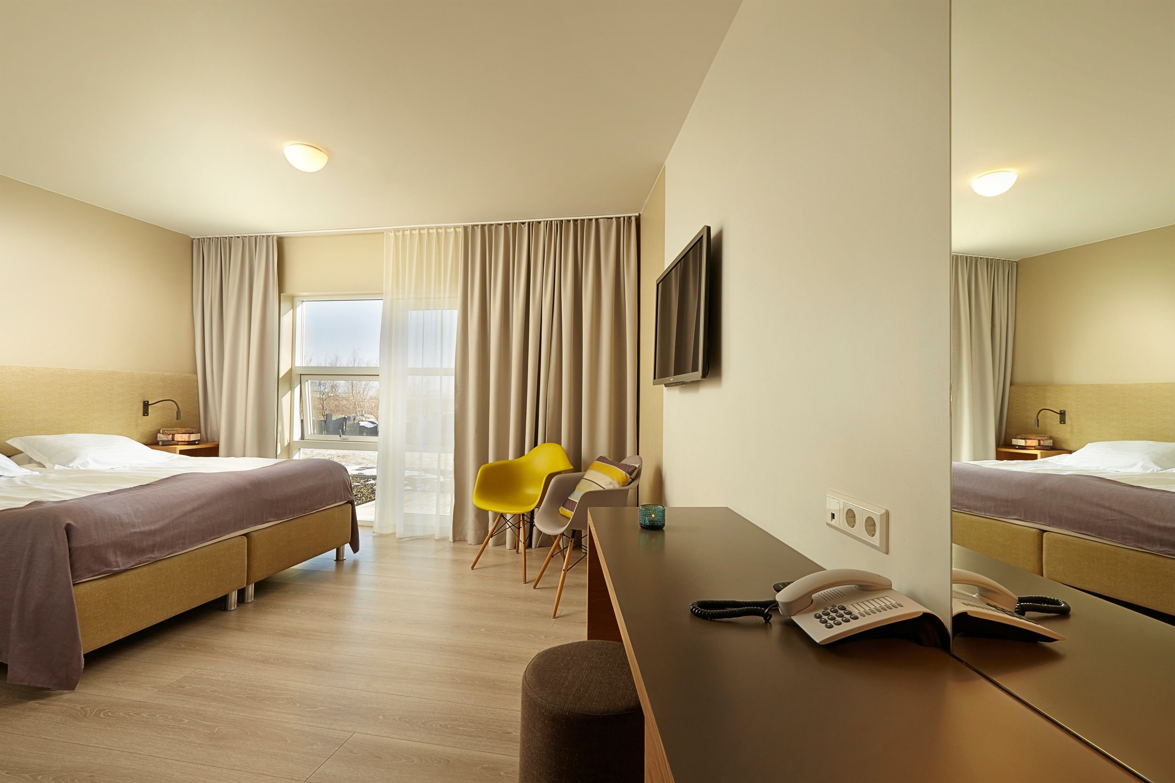 Ein Hotelzimmer mit zwei Betten, einem Schreibtisch mit Telefon und einem Stuhl.