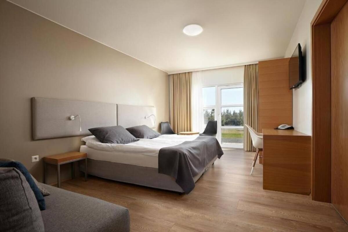 Una habitación de hotel moderna con cama, mesitas de noche, escritorio, silla y televisión.